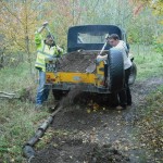 Yellow land rover with two people moving mud.