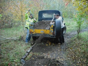 Yellow land rover with two people moving mud.