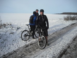 Three mountain bikers standing in snow.
