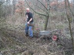 Trail builder filling wheel barrow with mud.