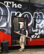 Man standing outside cafe bus with mop.