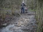 Man, wheelbarrow and hole full of rubble.