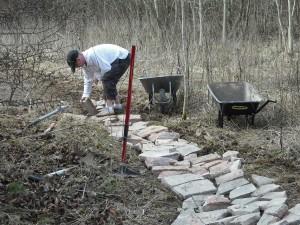 Placing bricks and rubble into bottom of mountain bike trail.