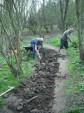 Digging mud out of mountain bike trail.