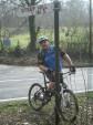 Mountain biker next to sign saying "steep hill".