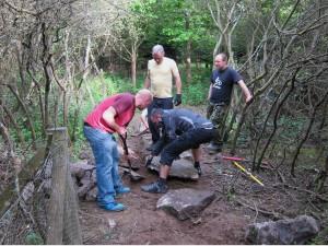 Placing rocks on mountain bike trail.