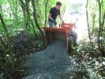 Power barrow tipping chippings onto trail.