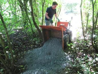 Power barrow tipping chippings onto trail.