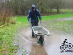 Wheel barrow through puddle.