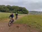 Mountain bikers riding on a gravel track in green countryside.