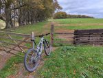 Mountain bike leaning against an open gate in a field.